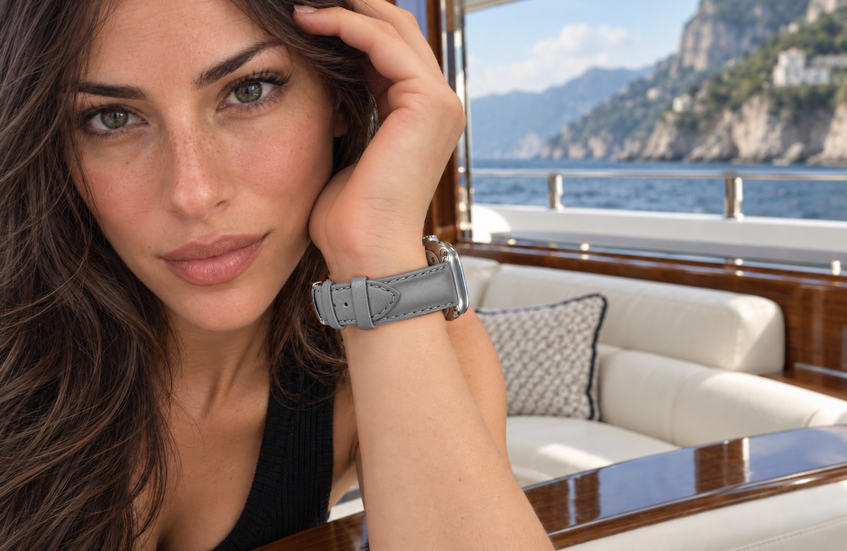 Woman wearing a padded WsC Defiant grey leather Apple Watch strap aboard a yacht, with standard non-diamond silver hardware.